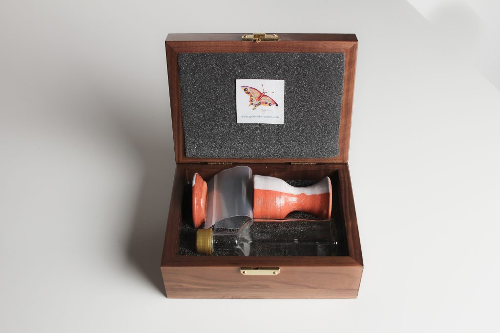 Small plastic bag for bread or wafers and glass wine bottle with spill proof cap (Glass is cleanable, and unlike the plastic ones you have used, glass will not stain over time). The glass bottle is dishwasher safe. If you do find a discoloration after many uses, swish a few grains of uncooked rice with a little water around in the bottle. Then scrub it clean!  Hand wash the plastic lid. Walnut box (made in USA), custom made to fit the set, with hard foam on the inside bottom of the box, which is carved to hold the set. Soft foam lines the lid to cushion the ceramics for travel.