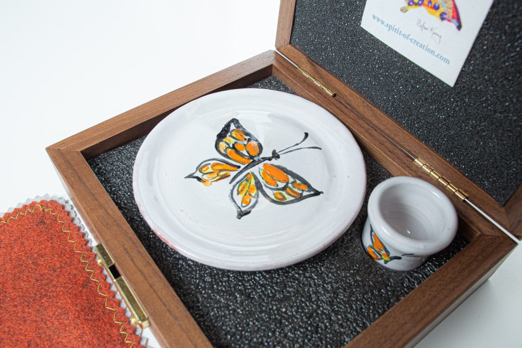 Walnut box (made in USA), custom made to fit the set, with hard foam on the inside bottom of the box, which is carved to hold the set. Soft foam lines the lid and supports the plate and cup to cushion the ceramics for travel.